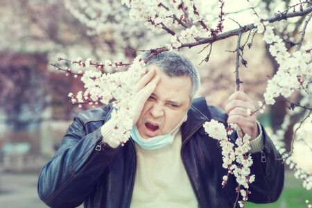 Man in a mask standing in the street and coughs.の写真素材