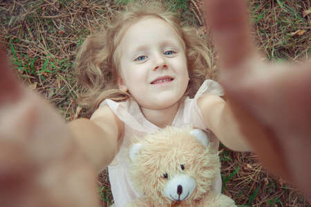 Portrait of a cute girl with a toy teddy bear close up.の写真素材