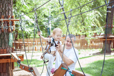 Young dad teaches his daughter to pass obstacles in an amusement parkの写真素材