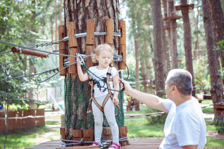 Young dad teaches his daughter to pass obstacles in an amusement parkの写真素材
