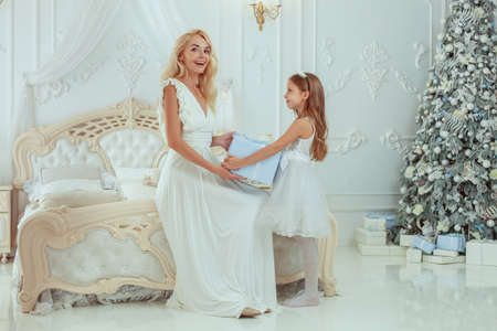 Girl gives a gift to her mother. Mom smiles with happiness.の写真素材