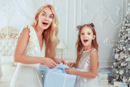 Mom and her daughter are opening a Christmas present. They are very surprised.の写真素材