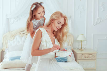 Beautiful mom opens a Christmas present. Her Daughter is peeping from behind.の写真素材