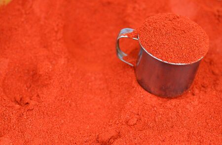Red background with paprika and a cup at the spice market