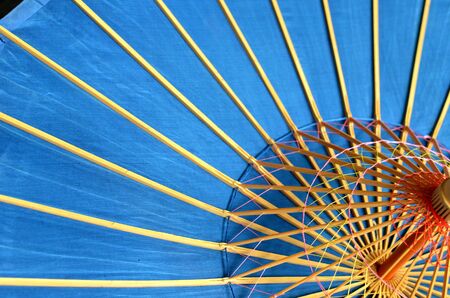 Beautiful sky blue background - vietnamese traditional  umbrella  with radial wooden ribs, close up photo, asian handicraft, diagonal compositionの写真素材