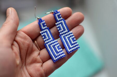 Handmade long dangle earrings with geometric blue and white design, unique design, hand with earringsの写真素材