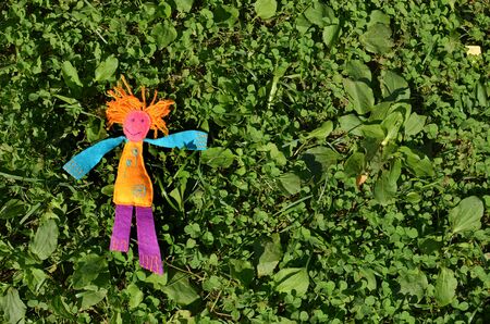 Handmade Colorful felt doll with orange hair lying on the green grass - concept of freedomの写真素材