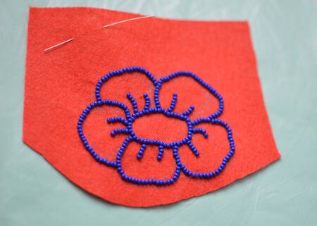 Process of making a flower beaded brooch - contour on felt embroided with blue beads - beginning...