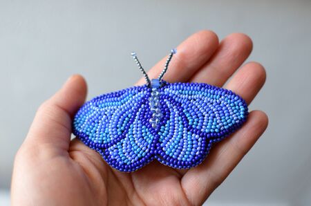 Handmade brooch of blue moth embroided with beads on a handの写真素材