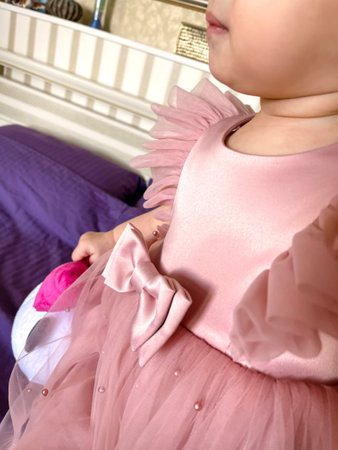 Dressed up little girl toddler in pink dress with bow, frills and fluffy mesh skirt. First Birthday party celebration photo.の写真素材
