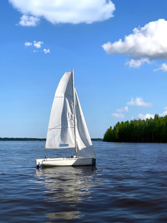 Photo of beautiful white sailing boat small yacht with sail on a summer day on the Volga river.の写真素材