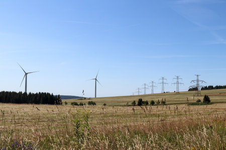 High voltage power lines and wind power plants in the mountain landscapeの写真素材
