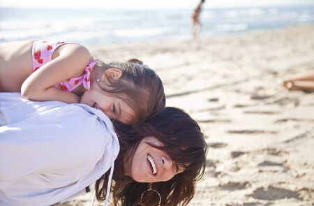Mom plays with her daughter on the beach