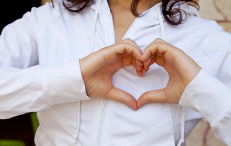 Woman forming a heart with hands on chestの写真素材