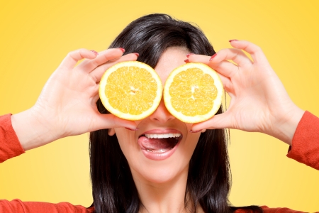 Young woman holding the oranges in front of your eyes with a cheerful and smilingの写真素材
