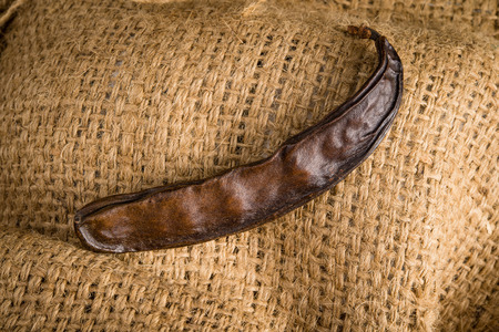Raw fruits Carob on old juta background