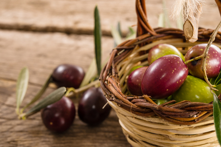 fresh olives in a basket, placed on a rustic wooden table. Olives from Sicily, Italyの写真素材