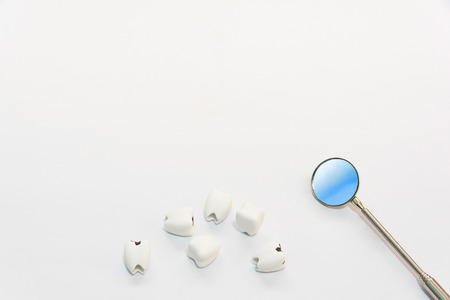 Dental care concept top view or flat lay of helathy teeth and bad teeth or caries with dentist mirror with copy space background on whiteの写真素材