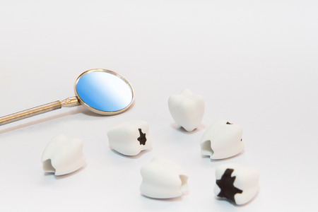 Dental care concept on white background with mirror dentist tool lay on table with healthy teeth and bad teeth or caries, selective focusの写真素材