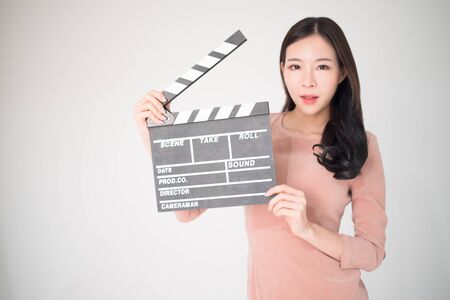 sian woman holding movie clapper board isolated on white background. Cinematography, communication arts, casting, audition, movie production concept. Movie clapper is the movie shooting equipment.の写真素材