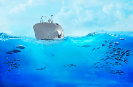 Small boat in the sea. Large school of fish in the ocean. Underwater world with sea animals.の写真素材