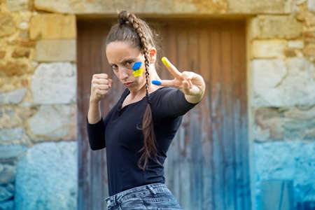 caucasian girl with braid and defense gesture supporting Ukraine in the war against russia. Blue and yellow background.の写真素材