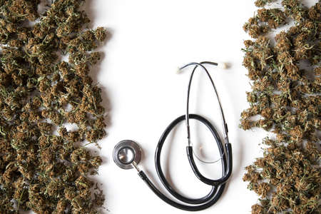 white background with space for copy. on the edges there are abundant dried marijuana buds and a phonendoscope to give a medical concept. legalize cannabis for medical treatment.の写真素材
