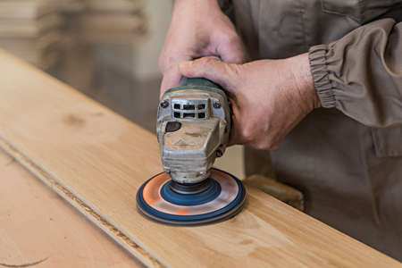 close up of carpenter's hand using a grinder on a wood surfaceの写真素材