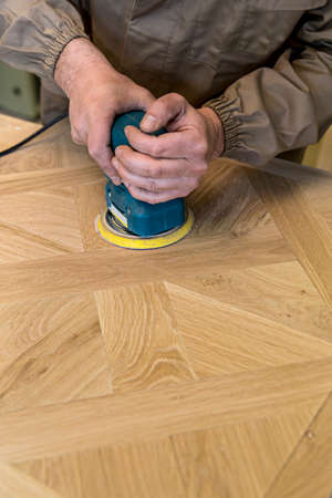 close up of carpenter's hand using a grinder on a wood surfaceの写真素材