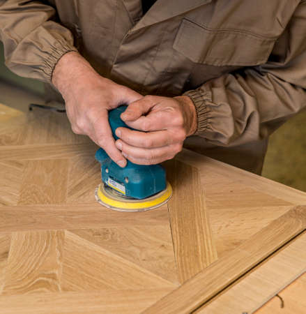 close up of carpenter's hand using a grinder on a wood surfaceの写真素材