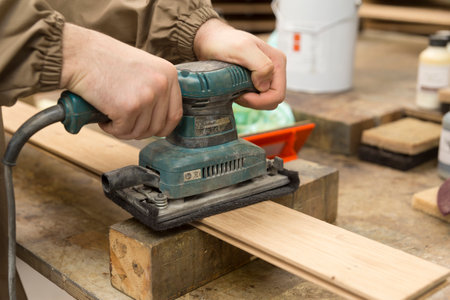 close up of carpenter's hand using a grinder on a wood surfaceの写真素材