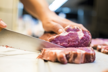 Chef cutting a slender piece of beef tenderloin with the background in blurの写真素材