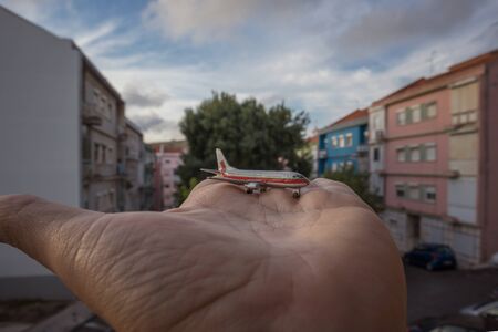 miniature airplane in hand palm overlooking the cityの写真素材