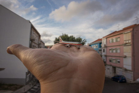 miniature airplane in hand palm overlooking the cityの写真素材