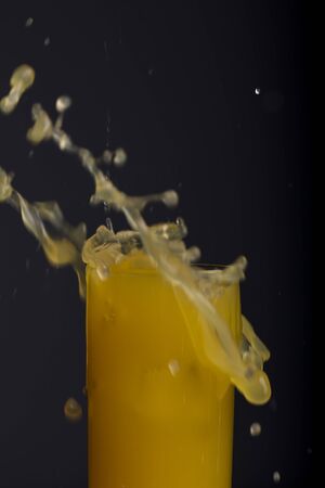 Glass of orange juice with splash, isolated on black backgroundの写真素材