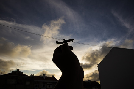 Hand of man holding miniature of airplane in silhouetteの写真素材