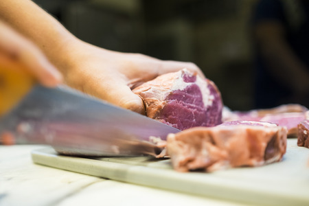 Chef cutting a slender piece of beef tenderloin with the background in blurの写真素材