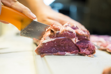 Chef cutting a slender piece of beef tenderloin with the background in blurの写真素材