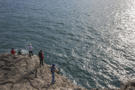 Fishermen fishing on rockの写真素材