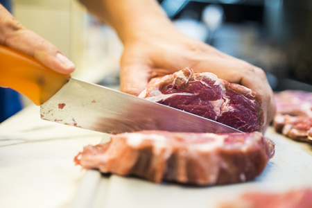 Chef cutting a slender piece of beef tenderloin with the background in blurの写真素材