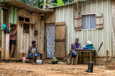 PRINCIPE/SAO TOME - 4 JAN 2016 - 3 native African individuals from Sao Tome  socialize at the door of houseのeditorial素材