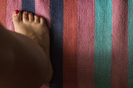 Woman's foot with colorful carpet in the backgroundの写真素材