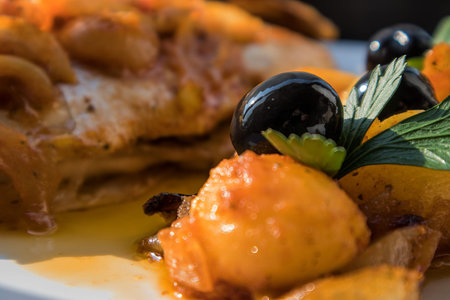 Fish baked in the oven, golden with boiled potatoes and olives in white dish. Typical Portuguese...