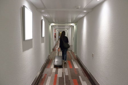 Girl walking in hotel corridor with suitcase.の写真素材