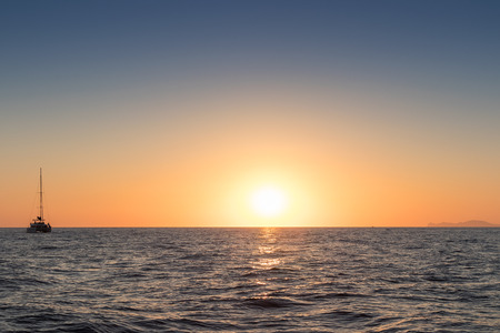 Beautiful sunset seen from the sea. With one catamaran Santorini, Greece.の写真素材
