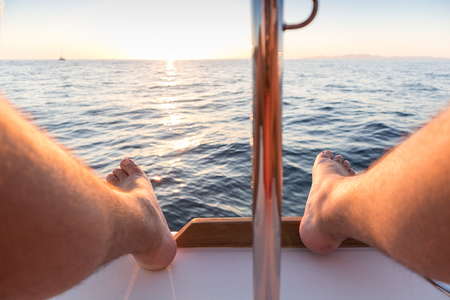 Feet of man with view of the sea and sunset.の写真素材