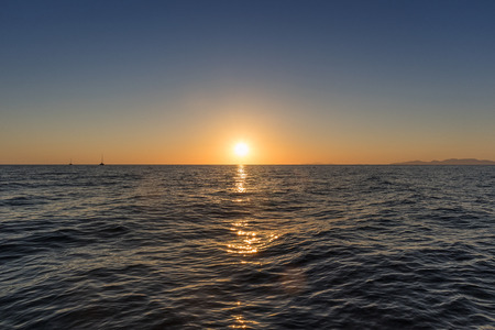 Beautiful sunset seen from the sea. With two catamaran Santorini, Greece.の写真素材