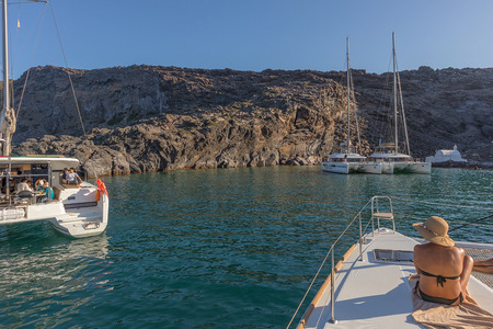 Woman sitting on the bow of boat, santorini greeceのeditorial素材