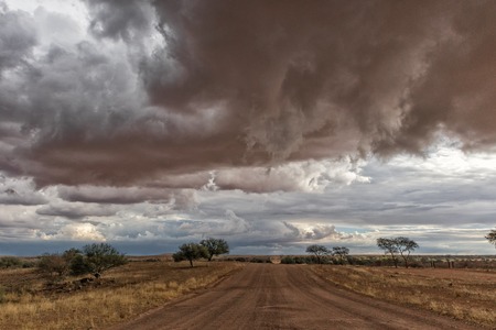Gravel road en route to the Namibian desert with extremely dramatic sky, storm.の写真素材