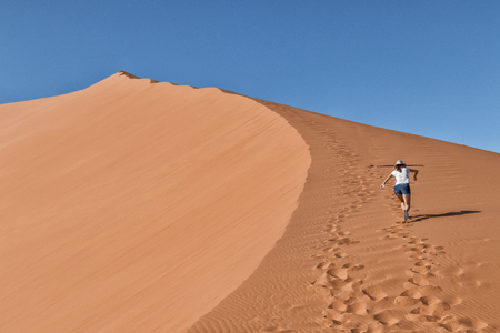 girl climbing red dune, Namibia. Sossusvlei.の写真素材